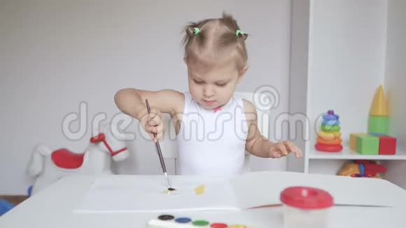 坐在桌子旁的小可爱女孩在相册里画画视频的预览图