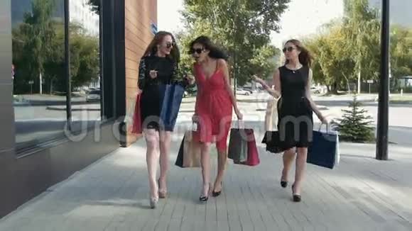 三位迷人的年轻女性走在市中心展示她们的购物视频的预览图
