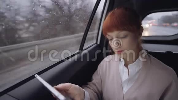 坐在车里的女人专注于她的平板电脑视频的预览图