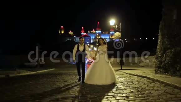 山上美丽的城堡夜晚岩石上的强化宫殿带有红色蓝色背光的毛巾两个人视频的预览图