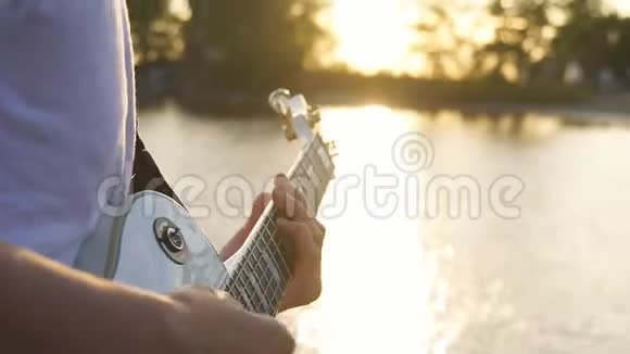 吉他手在户外傍晚日落时演奏电吉他和弦视频的预览图