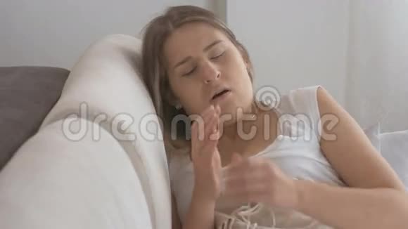 躺在沙发上的年轻生病妇女的特写镜头咳嗽和使用喉咙喷雾视频的预览图