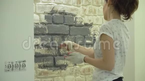 一个女孩用油漆刷画一堵灰色的砖墙视频的预览图