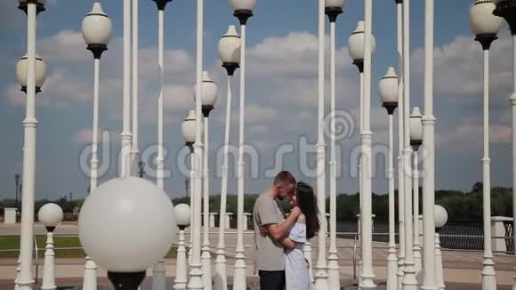 一对相爱的夫妇在路灯附近的堤岸上拥抱和亲吻视频的预览图