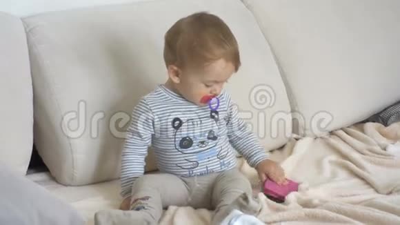 可爱的幼儿坐在沙发上试图打开智能手机视频的预览图