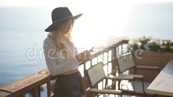 有智能手机的年轻女子在海边的咖啡馆聊天视频的预览图