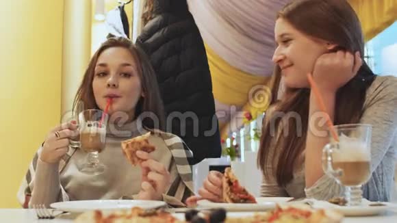 两个年轻的女学生朋友在咖啡馆里吃披萨和聊天秋天冬天视频的预览图