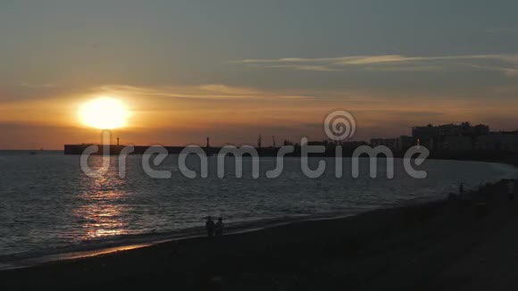 海滩和海湾与人在夕阳的灯光下视频的预览图