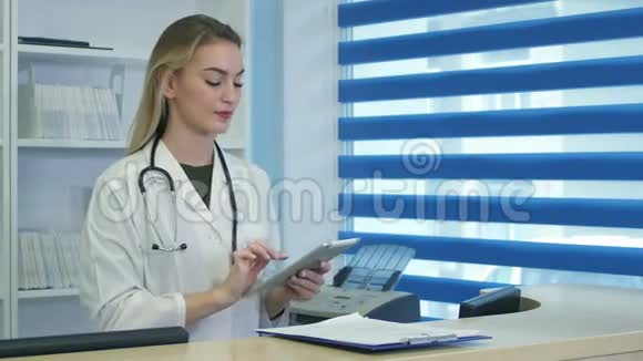 在医院前台使用平板电脑和电话的漂亮护士视频的预览图