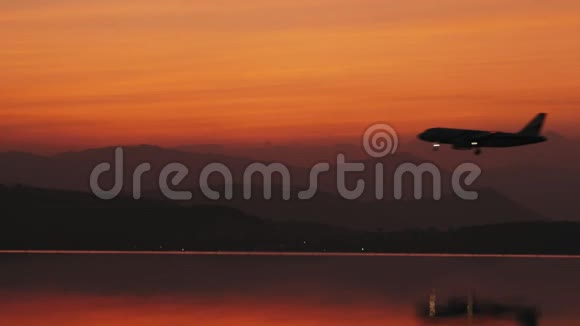 乘飞机降落在背景上美丽的日落在水中倒影视频的预览图