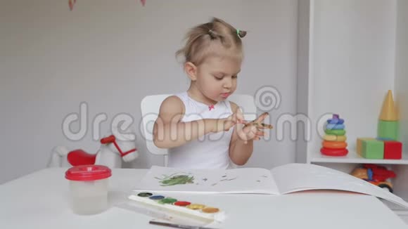 坐在桌子旁的小可爱女孩在相册里画画视频的预览图