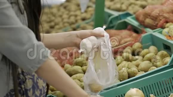 孕妇将洋葱放入透明塑料包装袋内女人的双手特写购物和人的概念视频的预览图