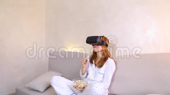 酷女孩用VR眼镜看视频晚上坐在明亮卧室的沙发上视频的预览图