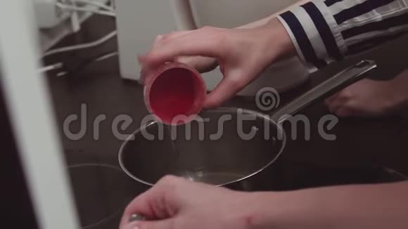 女厨师用手敲罐子在金属锅上涂上红色食用色素视频的预览图