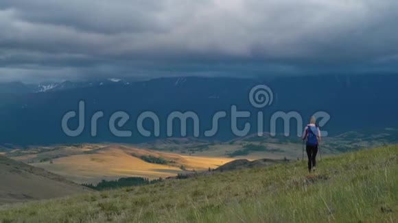 女人徒步旅行在山上远足带背包的女旅行者在美丽的夏季景观上视频的预览图