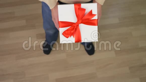 穿米色毛衣的白人男子手里拿着一个礼品盒穿着休闲米色毛衣的人的俯视图男人送礼物视频的预览图