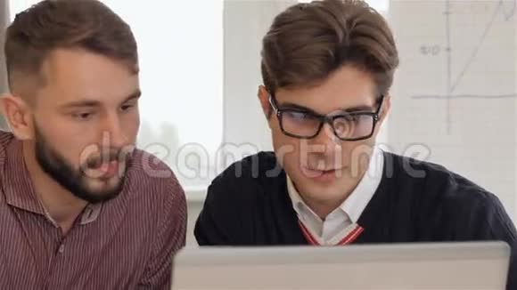 戴眼镜的男人向他的男性同事解释笔记本电脑上的东西视频的预览图