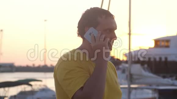 年轻的快乐男人在日落的海船上用手机说话3840x2160视频的预览图