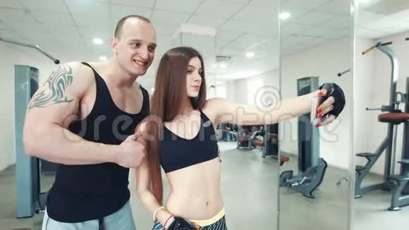 长发女运动员和纹身男在健身房自拍视频的预览图