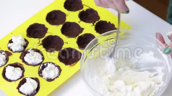 那个女人用一种涂有融化巧克力的形状填充凝乳团桌子旁边是烹饪的原料视频的预览图