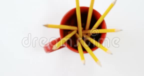 白色背景下的红色马克杯中的黄色铅笔视频的预览图