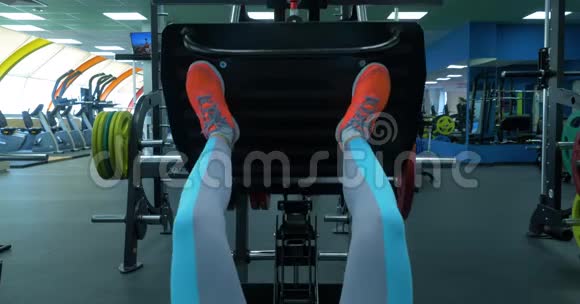 在健身房里做压腿动作的一个年轻女子的鞋一位身材匀称的年轻女子在腿部按压的特写镜头视频的预览图