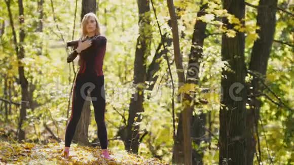女人在户外做健身运动在秋天的森林里女人伸展手臂户外运动的苗条女孩视频的预览图