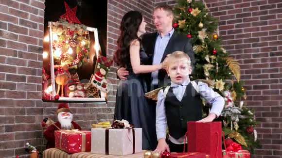 父母在浪漫的环境中情人父母跳舞孩子在圣诞树附近玩圣诞礼物视频的预览图