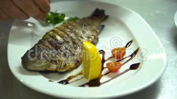 厨房餐厅做饭厨师把青菜和鱼放在盘子里视频的预览图
