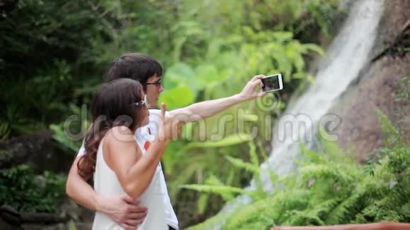 幸福夫妇自拍照片与美丽的瀑布背景1920x1080视频的预览图