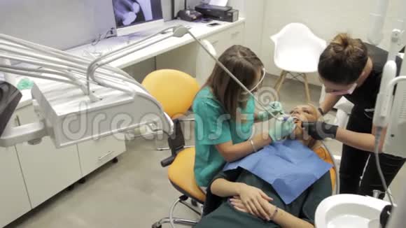 一位女牙医和她的助手在研究病人的牙齿视频的预览图