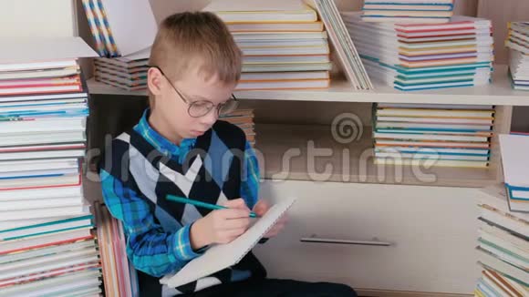 七岁戴眼镜的男孩在一本坐在书中的素描书中画了一些东西视频的预览图