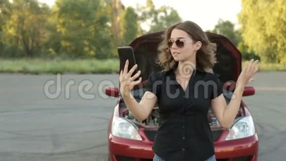一个激动的女孩和一辆破车在路上给汽车服务部门打电话视频的预览图