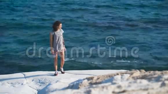 一位年轻女子穿着一件长t恤站在海边视频的预览图
