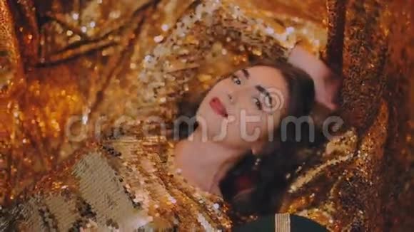 穿金色连衣裙的女孩躺在金色的背景上红色口红帕特视频的预览图
