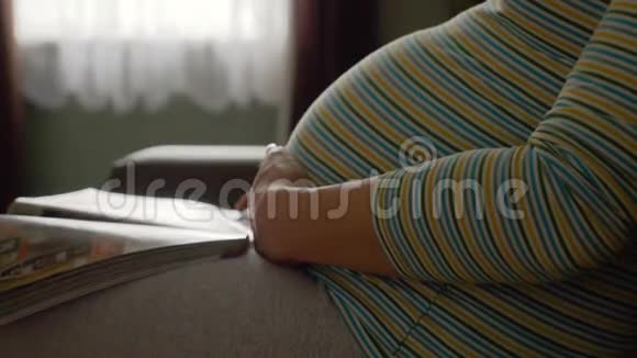 坐在沙发上翻杂志页的孕妇视频的预览图