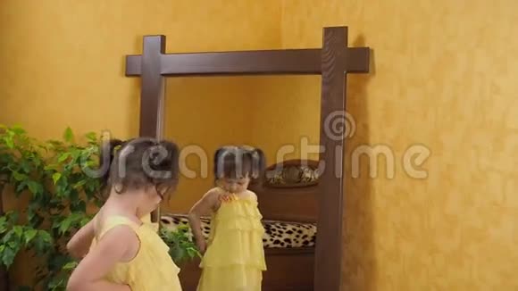 一个害羞的小女孩照镜子穿着黄色裙子的漂亮女孩对着镜子头上有尾巴的孩子视频的预览图