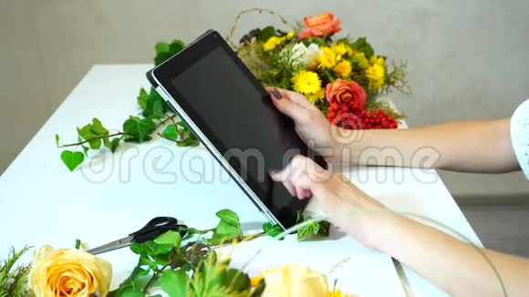 在办公室里花店女孩的手在桌上的花安排中牵着手指的特写视频的预览图