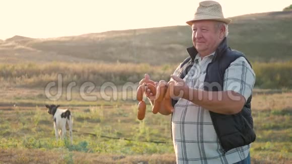 快乐的成年农夫微笑着看着镜头手里拿着香肠手里拿着一群奶牛在农场的牛棚里农业视频的预览图