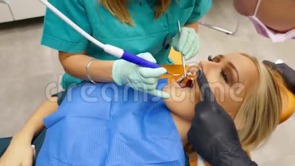 一位牙医和她的助手在研究病人的牙齿视频的预览图