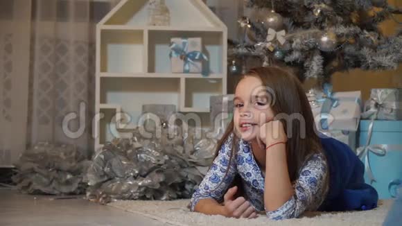 女孩躺在圣诞树下的地板上甜甜地笑视频的预览图