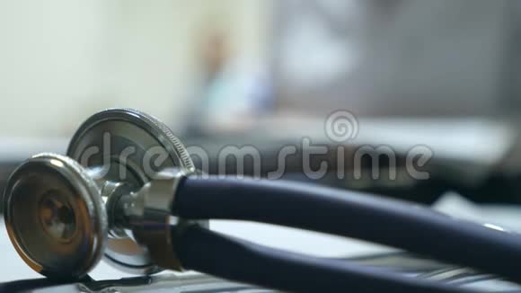 听诊器接近前景年轻护士在办公桌工作并在后台书写病历女性视频的预览图