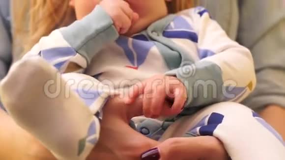 宝宝的特写咀嚼她的手指同时坐在妈妈的手上视频的预览图