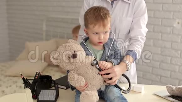 医生和男孩在医院用听诊器检查泰迪熊视频的预览图
