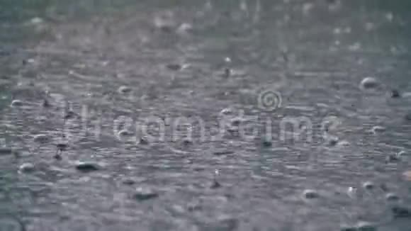 暴雨时大滴的雨落在水坑里水滴在慢运动中视频的预览图