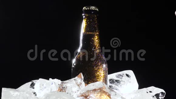 节日一个男人拿出一瓶带冰的啤酒黑色背景快关门慢动作视频的预览图