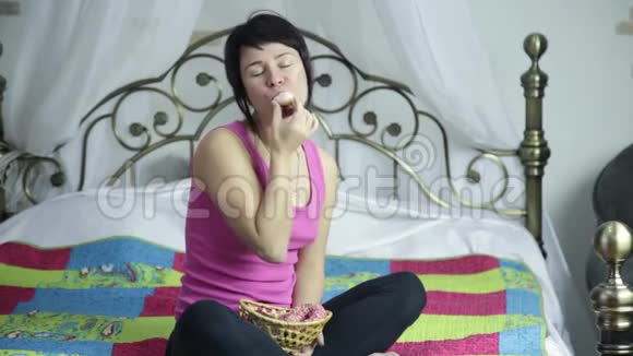 运动女孩在床上快乐地吃甜甜圈禁止吃垃圾食品视频的预览图