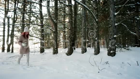 女孩在冬天穿过树林拿着蜡烛年轻的女人自信地走在雪地上视频的预览图