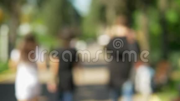 离焦背景阳光明媚的夏季公园人们散步视频的预览图