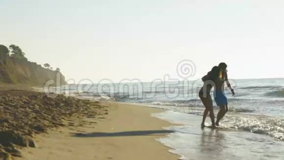快乐的年轻夫妇在海边玩海浪在沙滩上帅哥抱着漂亮女孩视频的预览图
